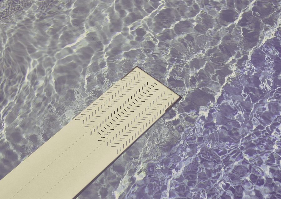 A flush outlet set into the floor of a shallow water plaza.