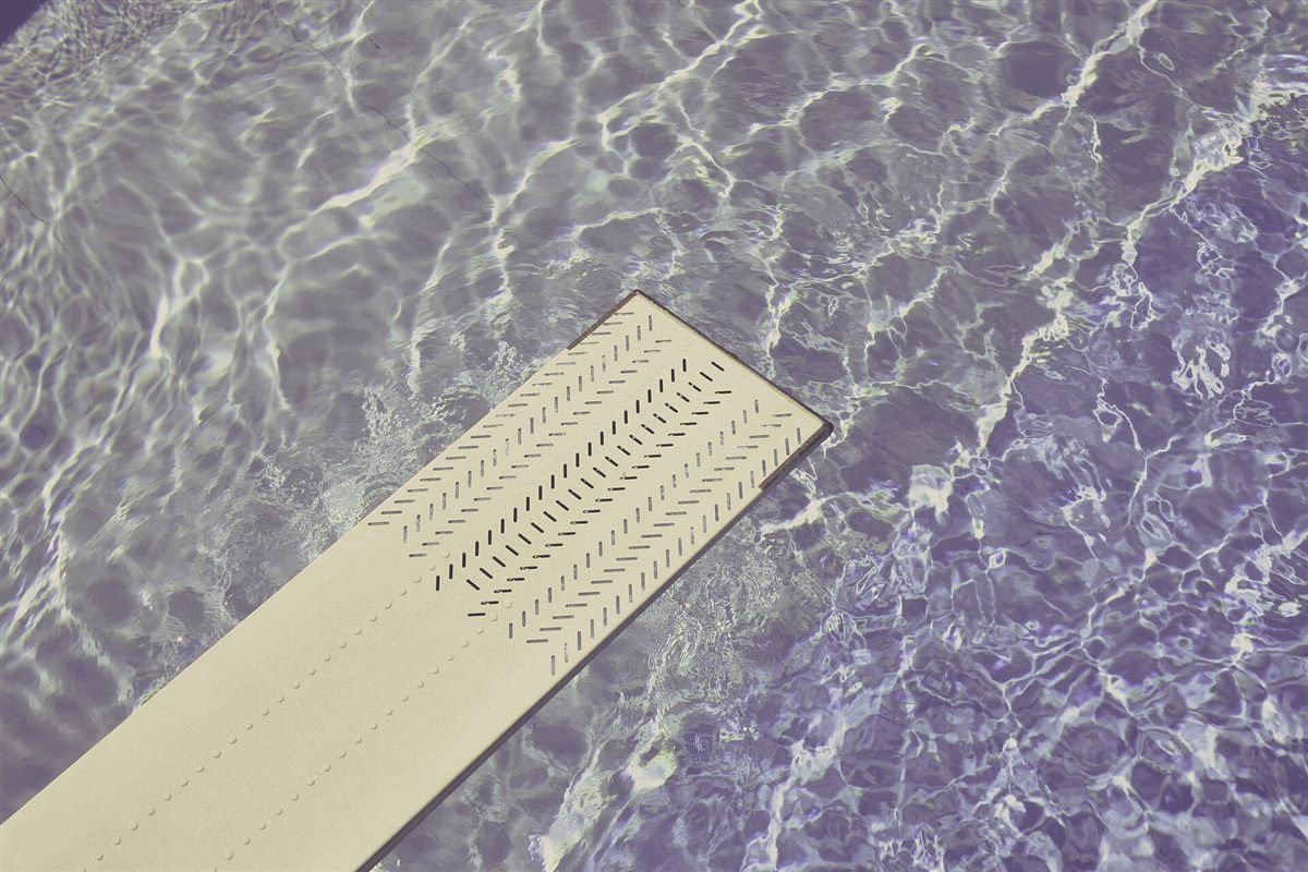 A flush outlet set into the floor of a shallow water plaza.